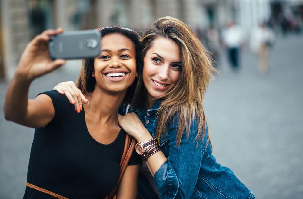 Image of a black girl and white girl taking a selfie in the UK