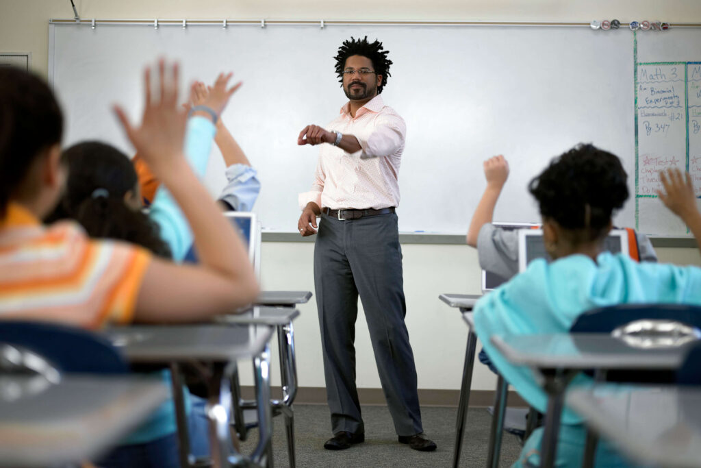 Image of a black male teacher teaching his students in a classroom located in a county in the UK