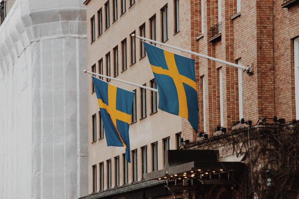 Image of the flags of Sweden swinging in front of houses downtown