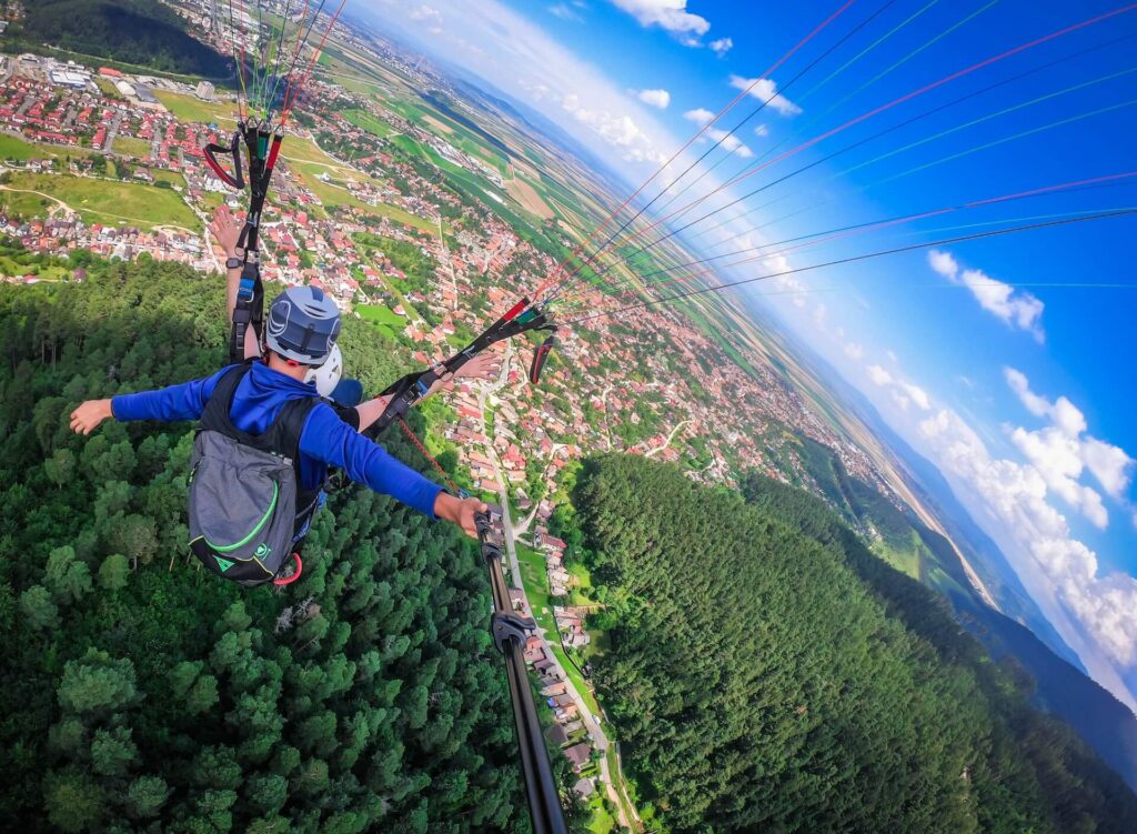 A man taking pictures of himself while sky diving with a parachute on. The best travel insurance for adventure sports