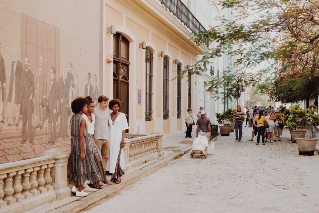 The streets of Cuba, with 3 individuals standing about talking