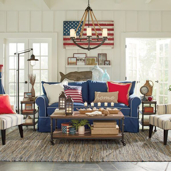 U.S home décor style that shows the through pillows made of the U.S flag, sofas, a center table, a chandelier and other furniture.