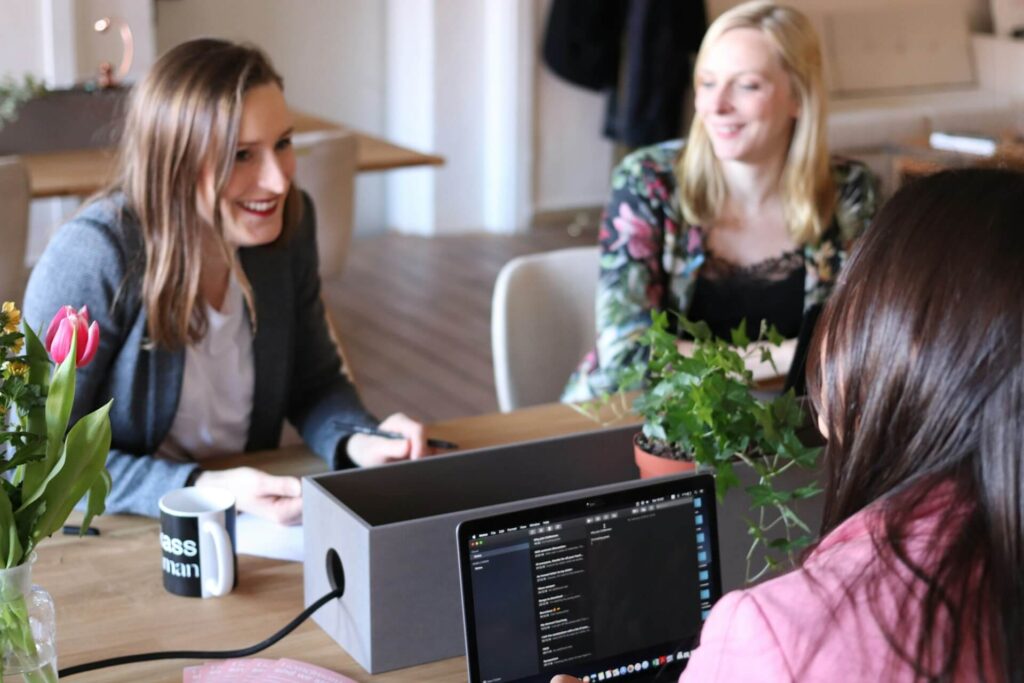 3 women in the office talking about a service offered by a travel agency