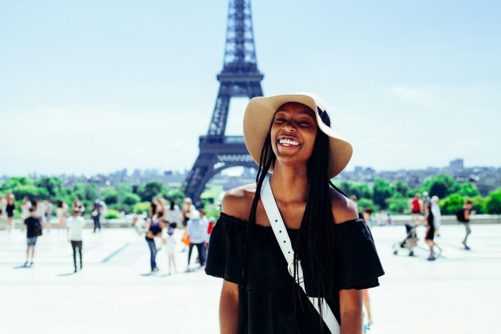 A black lady taking a picture in front of the Eiffel tower while on holiday