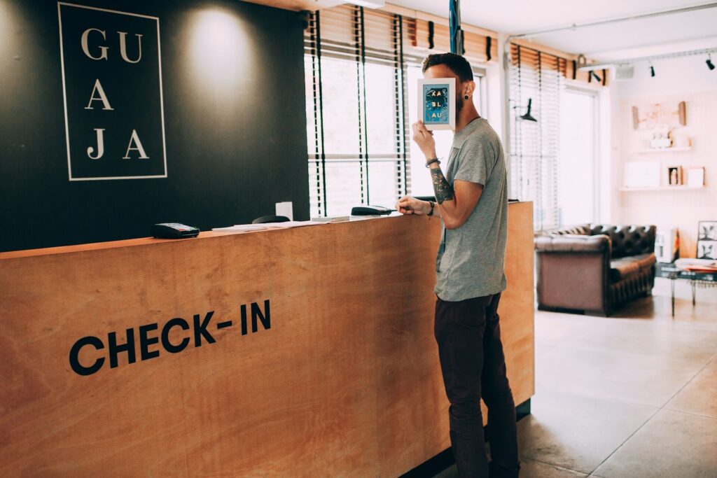 A man covering his face while standing in front of hotel's check in desk