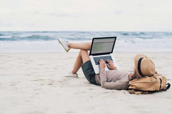A woman on the beach working on her laptop